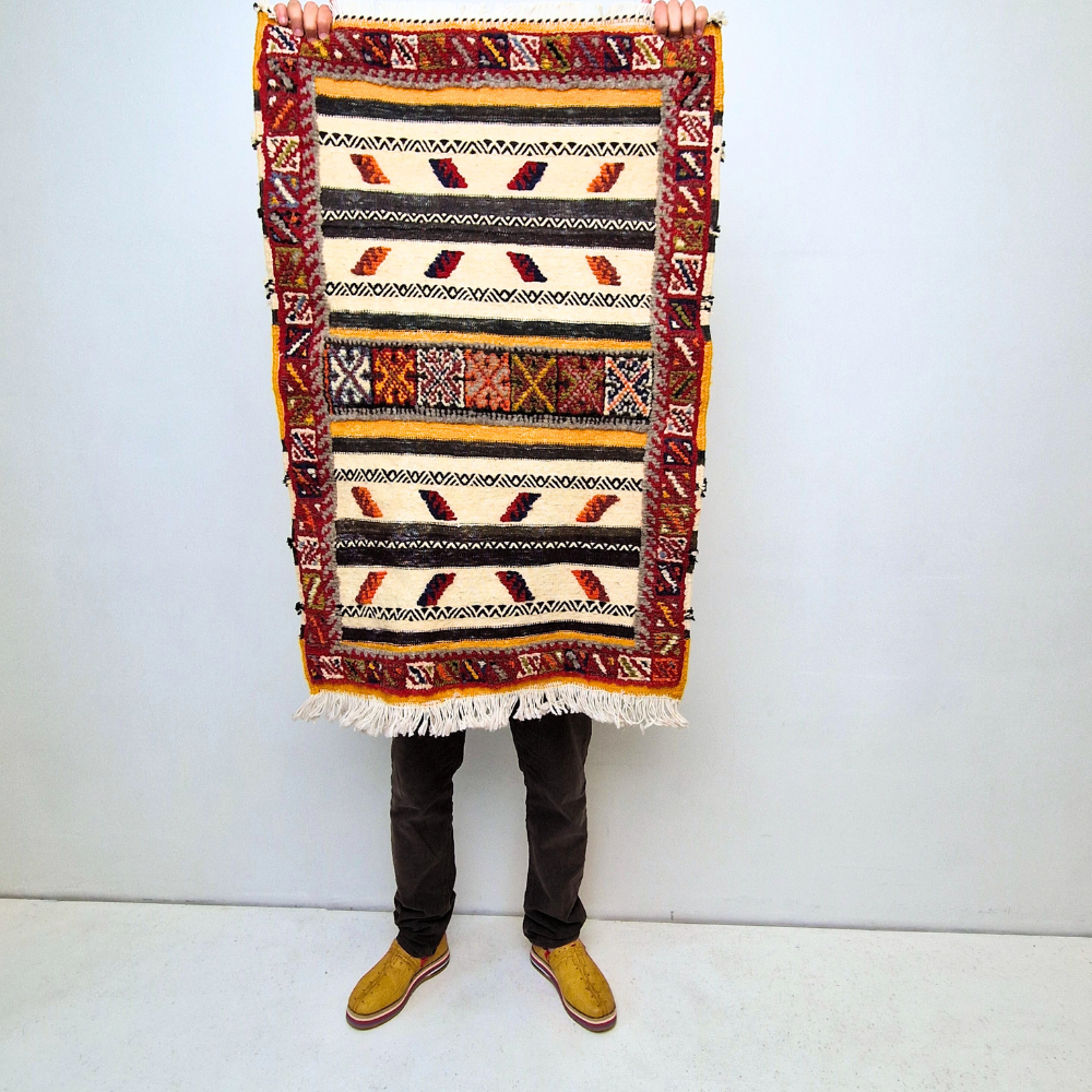 Bohemian Moroccan Azilal rug with bold geometric patterns in red, blue, white and multicolor wool, featuring abstract Berber tribal motifs and handwoven texture.