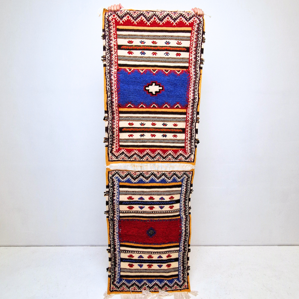 Bohemian Moroccan Azilal rug with bold geometric patterns in red, blue, white and multicolor wool, featuring abstract Berber tribal motifs and handwoven texture.