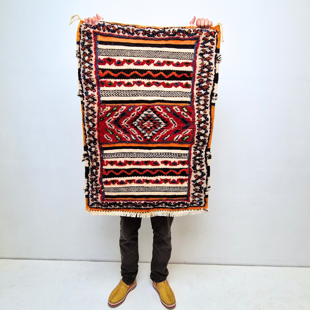 Bohemian Moroccan Azilal rug with bold geometric patterns in red, blue, white and multicolor wool, featuring abstract Berber tribal motifs and handwoven texture.