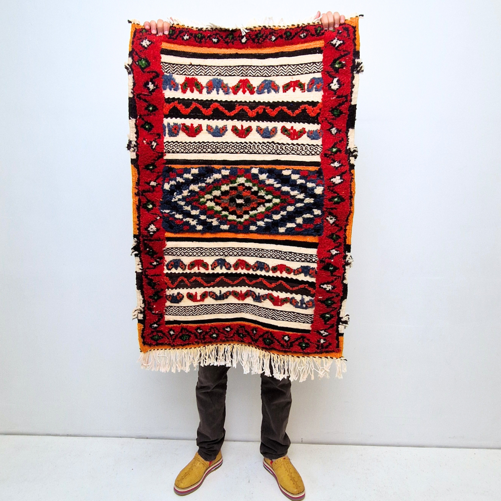 Bohemian Taznakht Handmade Small Rug with bold geometric patterns in red, blue, white and multicolor wool, featuring abstract Berber tribal motifs and handwoven texture.