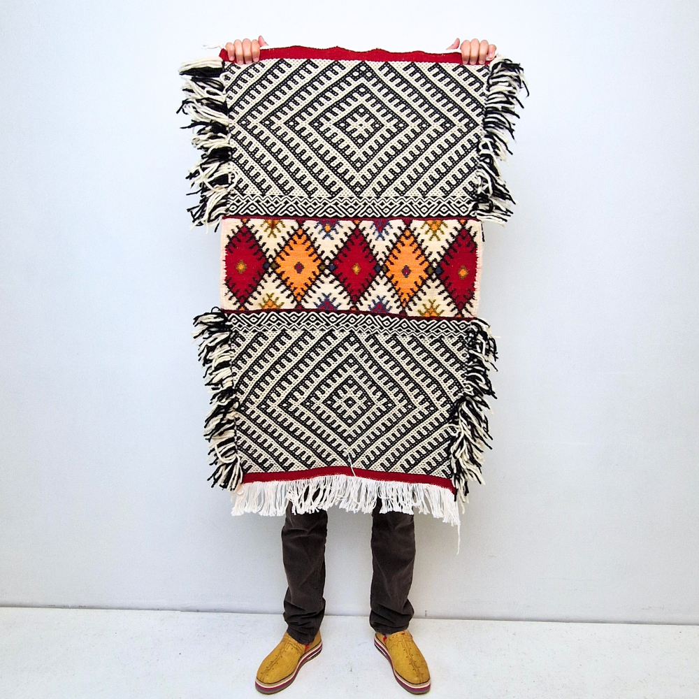 Bohemian Moroccan Azilal rug with bold geometric patterns in red, blue, white and multicolor wool, featuring abstract Berber tribal motifs and handwoven texture.