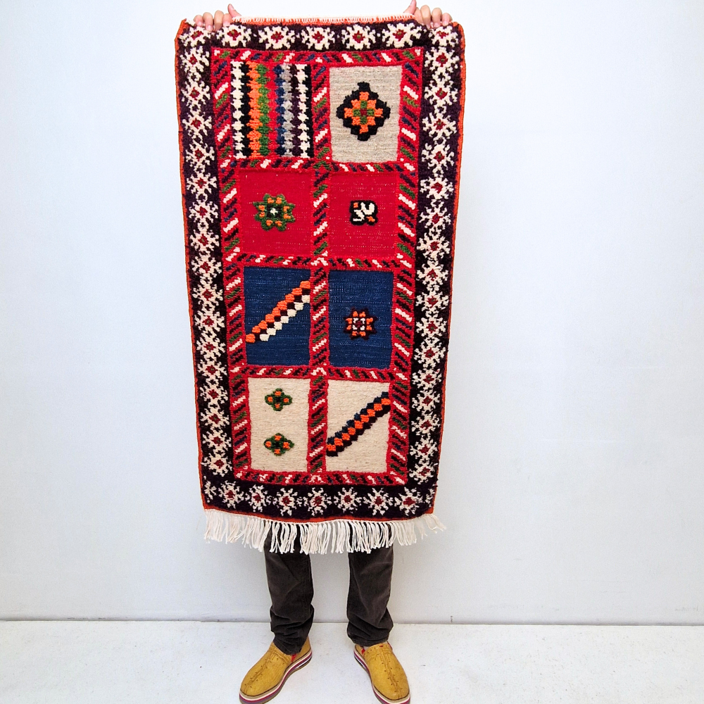 Bohemian Moroccan Azilal rug with bold geometric patterns in red, blue, white and multicolor wool, featuring abstract Berber tribal motifs and handwoven texture.