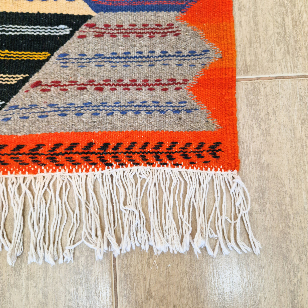 Bohemian Moroccan Azilal rug with bold geometric patterns in red, blue, white and multicolor wool, featuring abstract Berber tribal motifs and handwoven texture.