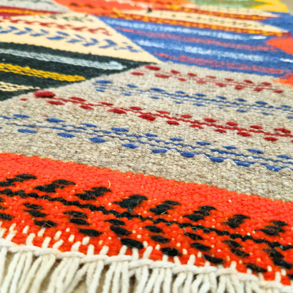 Bohemian Moroccan Azilal rug with bold geometric patterns in red, blue, white and multicolor wool, featuring abstract Berber tribal motifs and handwoven texture.