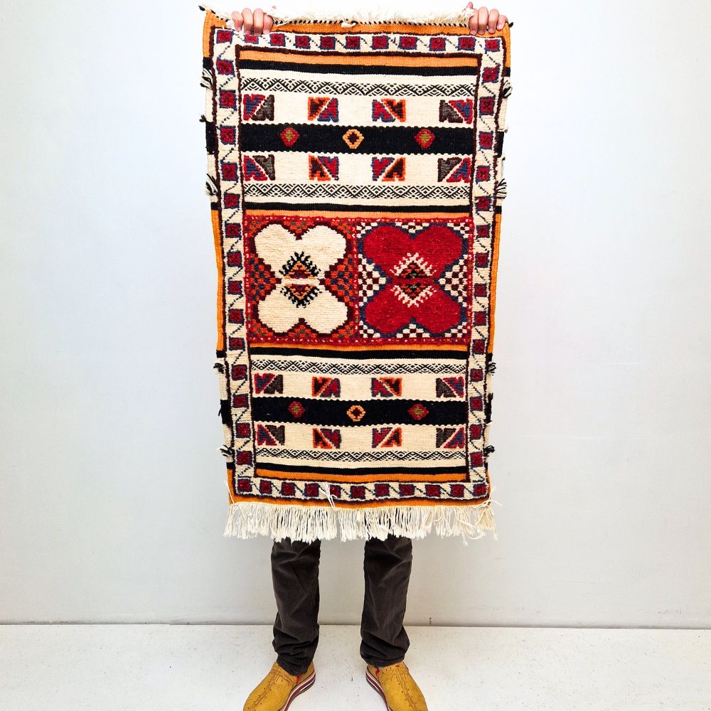 Bohemian Moroccan Azilal rug with bold geometric patterns in red, blue, white and multicolor wool, featuring abstract Berber tribal motifs and handwoven texture.