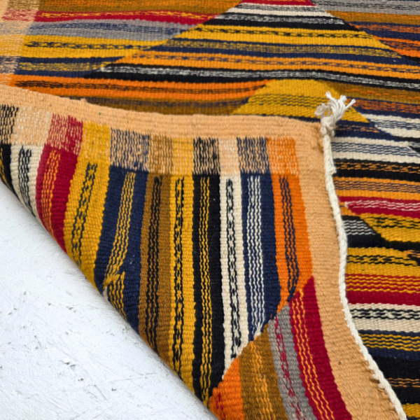 Bohemian Moroccan Azilal rug with bold geometric patterns in red, orange, purple, and multicolor wool, featuring abstract Berber tribal motifs and handwoven texture.