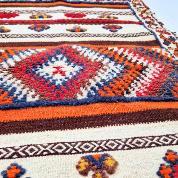 Bohemian Moroccan Azilal rug with bold geometric patterns in red, blue, white and multicolor wool, featuring abstract Berber tribal motifs and handwoven texture.