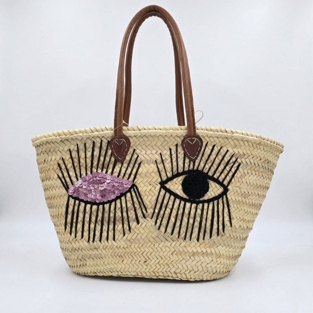 Winking eye basket bag with black thread eye, pink sequin eye, and leather handles